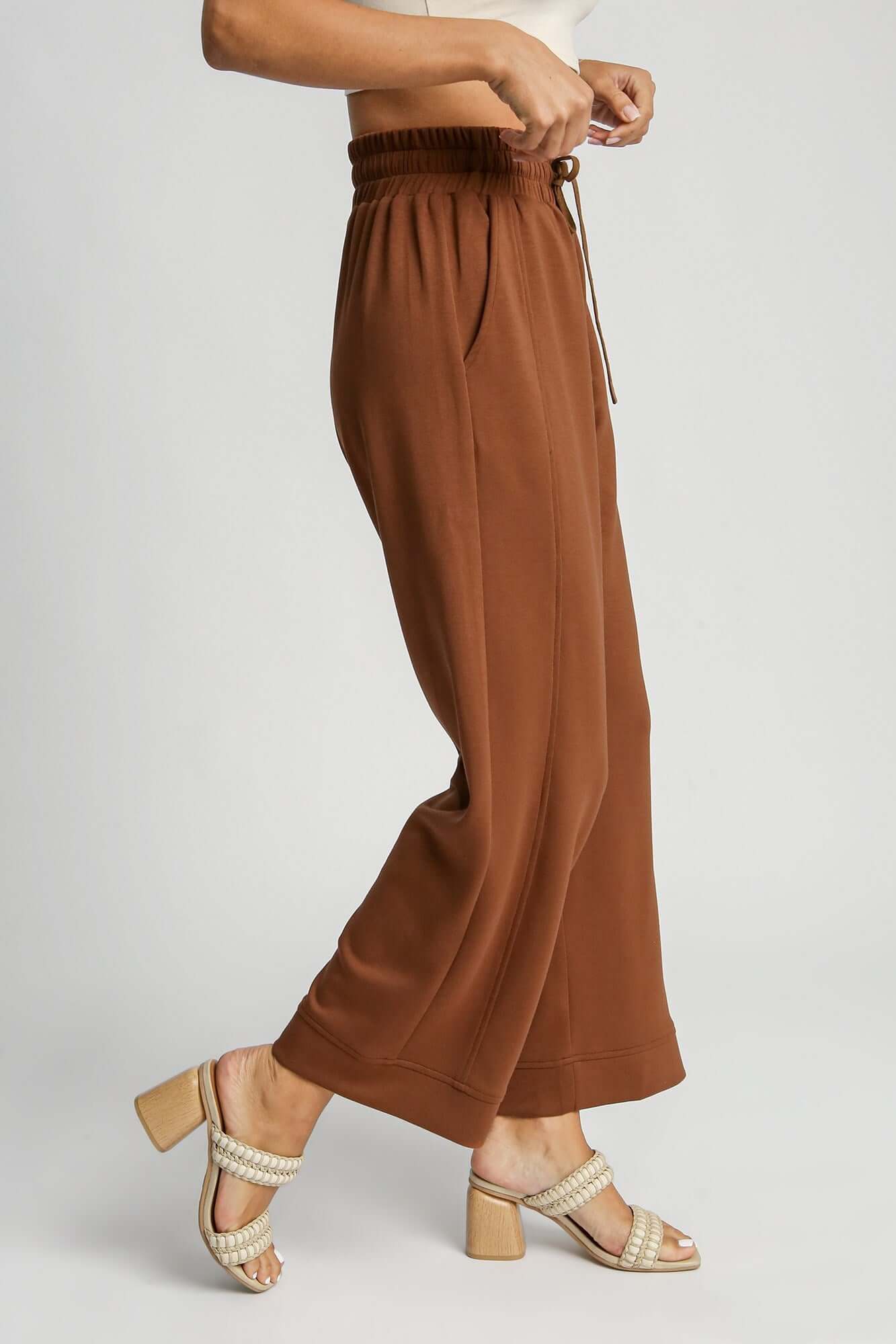 Umgee drawstring wide leg pants in brown, showcasing a relaxed fit and convenient side pockets, paired with stylish heels.