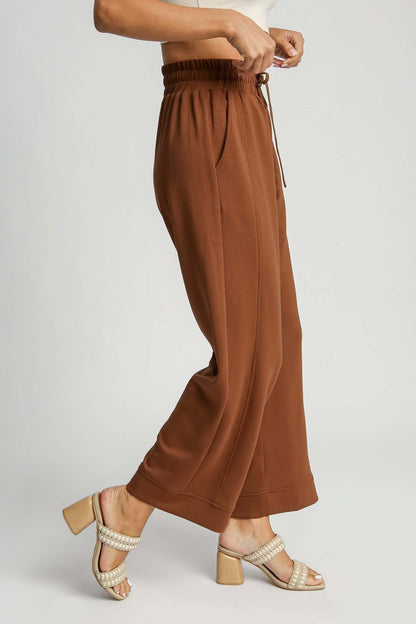 Umgee drawstring wide leg pants in brown, showcasing a relaxed fit and convenient side pockets, paired with stylish heels.