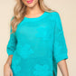 Woman wearing a turquoise floral crochet side slit knit top paired with jeans for a stylish casual look