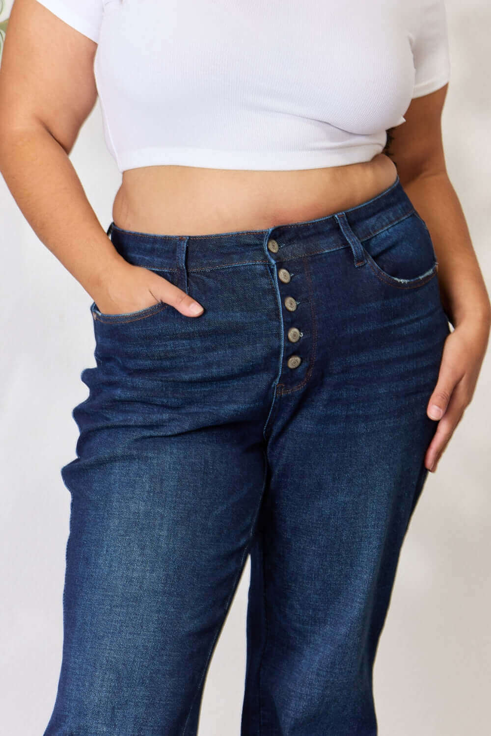 Woman wearing high waist button-fly straight Judy Blue Jeans with a white crop top.