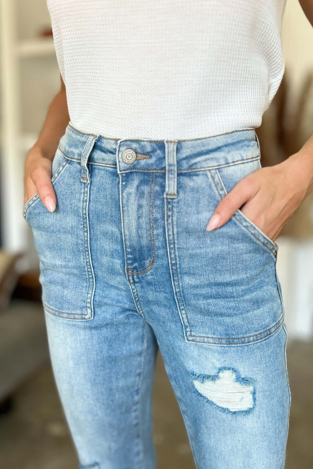 Woman wearing Judy Blue distressed straight jeans with patch pockets and a white top.