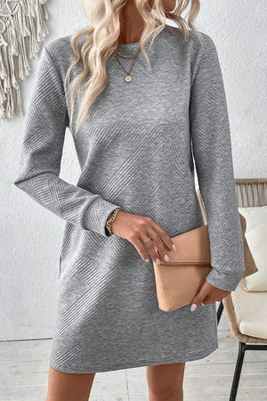 Stylish woman in a gray textured long sleeve mini dress holding a clutch, perfect for casual outings.