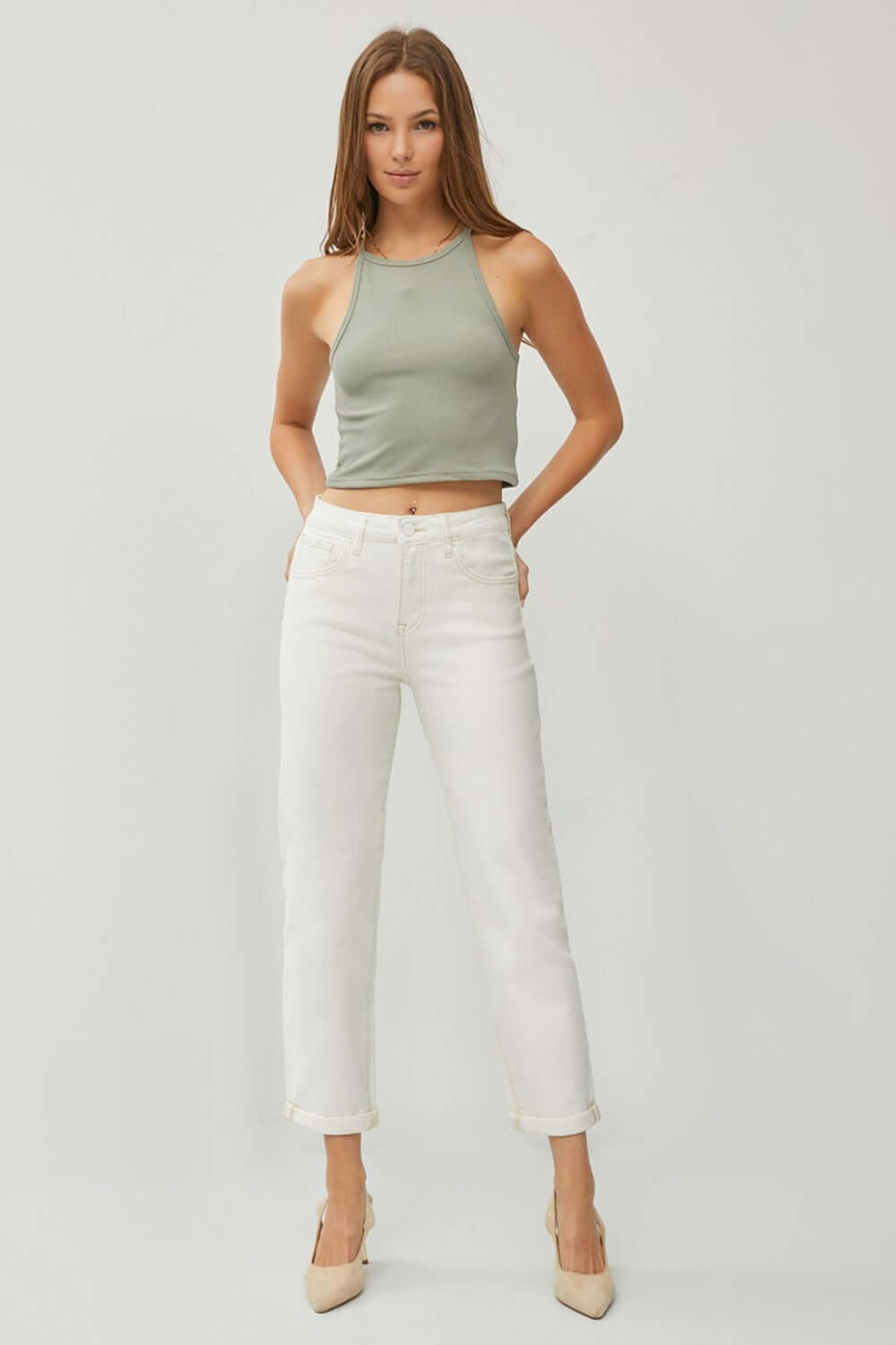 Woman wearing RISEN full size high waist rolled hem straight jeans in white paired with a green tank top.