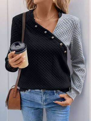 Woman wearing a Perfee Decorative Button Contrast Long Sleeve Sweatshirt in black and gray, holding a coffee cup.