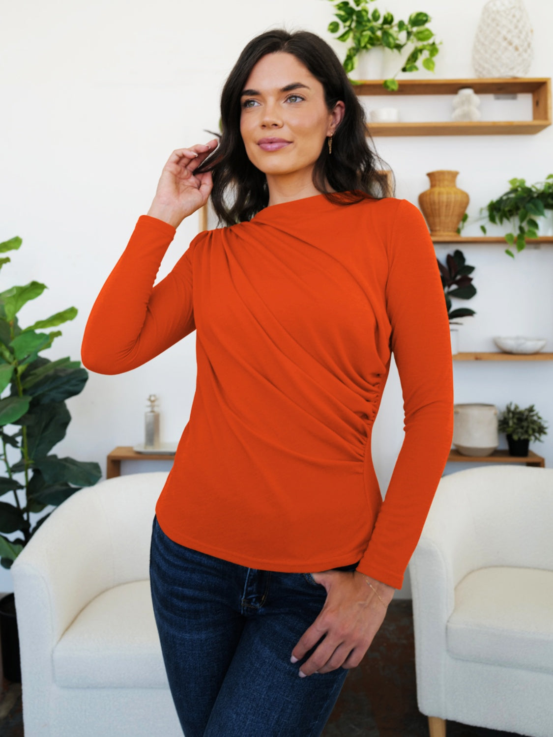 Woman modeling an orange FAM-FAM Ruched Mock Neck Long Sleeve T-Shirt, perfect for fall layering and style, in a cozy room setting.