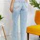 Back view of woman wearing high waist light wash Allie 90's Dad Jean with distressed detailing and raw hem, standing near yellow chair.