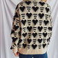 Woman wearing Bella Road Heart Contrast Long Sleeve Dropped Shoulder Sweater with heart pattern, standing against white backdrop