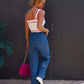 Woman wearing embroidered straight jeans with pockets, white top, and pink purse.