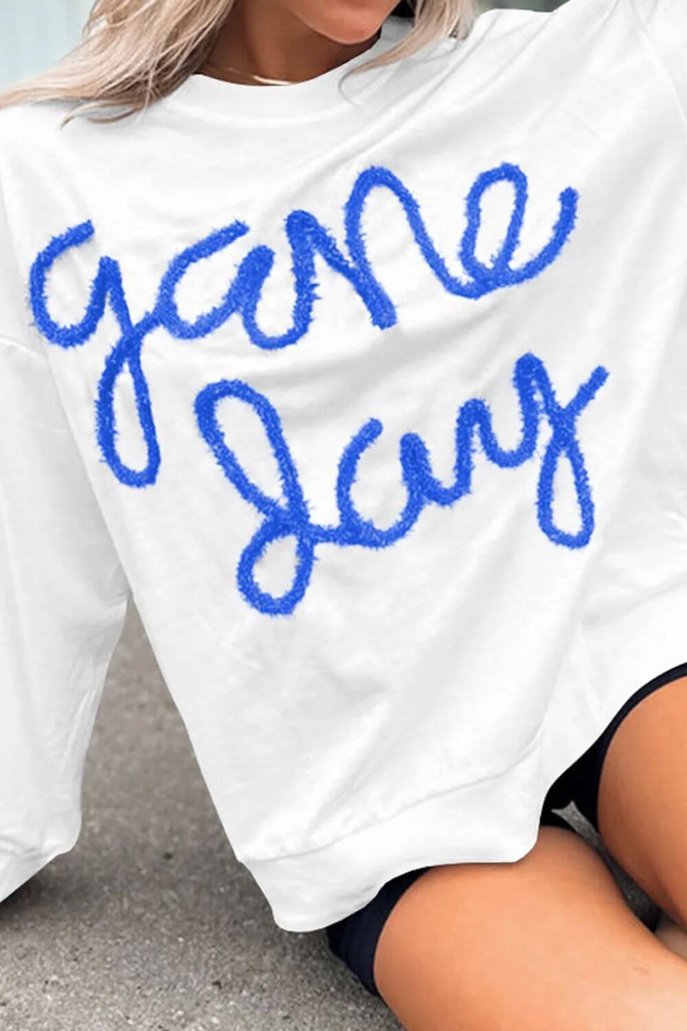 Woman wearing a Bella Road Game Day Round Neck Long Sleeve Sweatshirt with "game day" written in blue letters