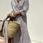 Woman wearing Bella Road Tied Button Up Three-Quarter Sleeve Dress and holding a woven tote bag on a sunny day.