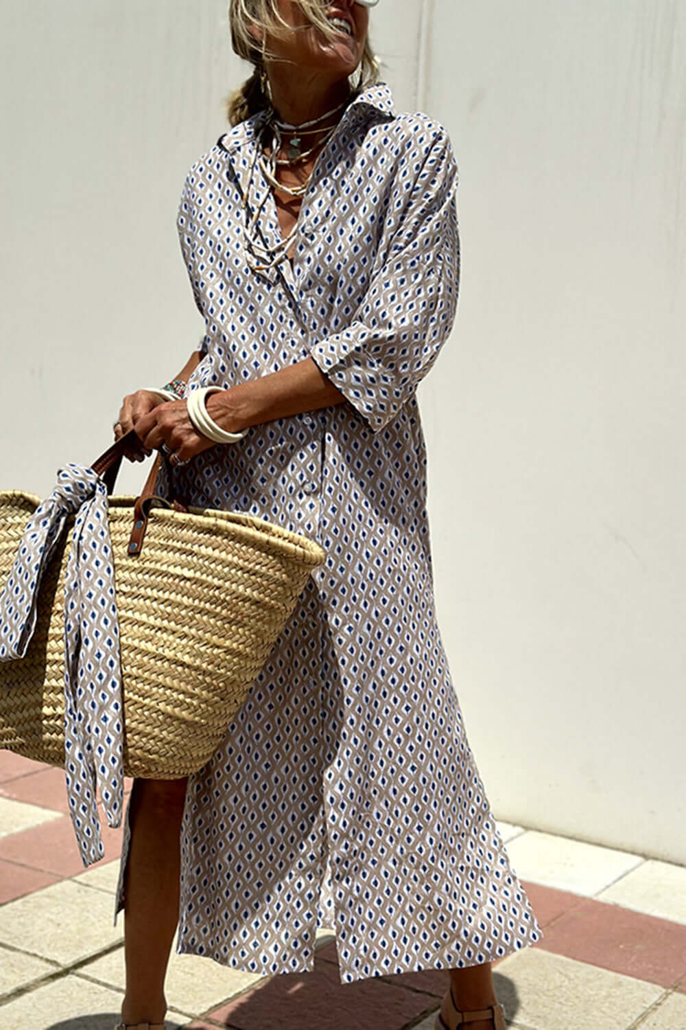 Woman wearing Bella Road Tied Button Up Three-Quarter Sleeve Dress and holding a woven tote bag on a sunny day.