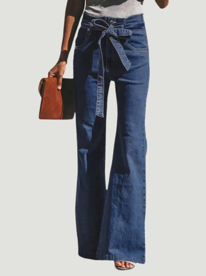 Woman wearing Tied Flare Jeans with Pockets and holding a brown clutch, showcasing stylish and comfortable pocketed denim with moderate stretch.