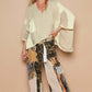 Stylish model wearing a high-low contrast V-neck top with oversized fit, paired with eclectic patterned wide-leg pants.