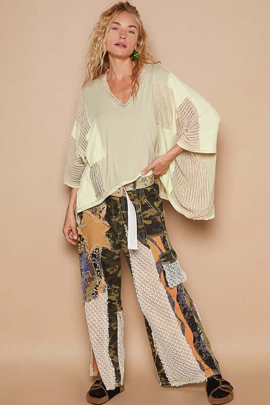 Stylish model wearing a high-low contrast V-neck top with oversized fit, paired with eclectic patterned wide-leg pants.