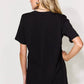 Woman wearing a black graphic round neck short sleeve t-shirt with slightly stretchy material, shown from the back.