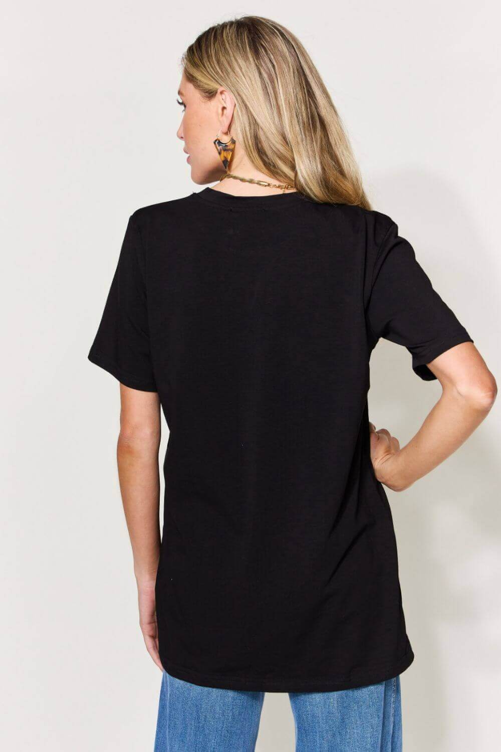 Woman wearing a black graphic round neck short sleeve t-shirt with slightly stretchy material, shown from the back.