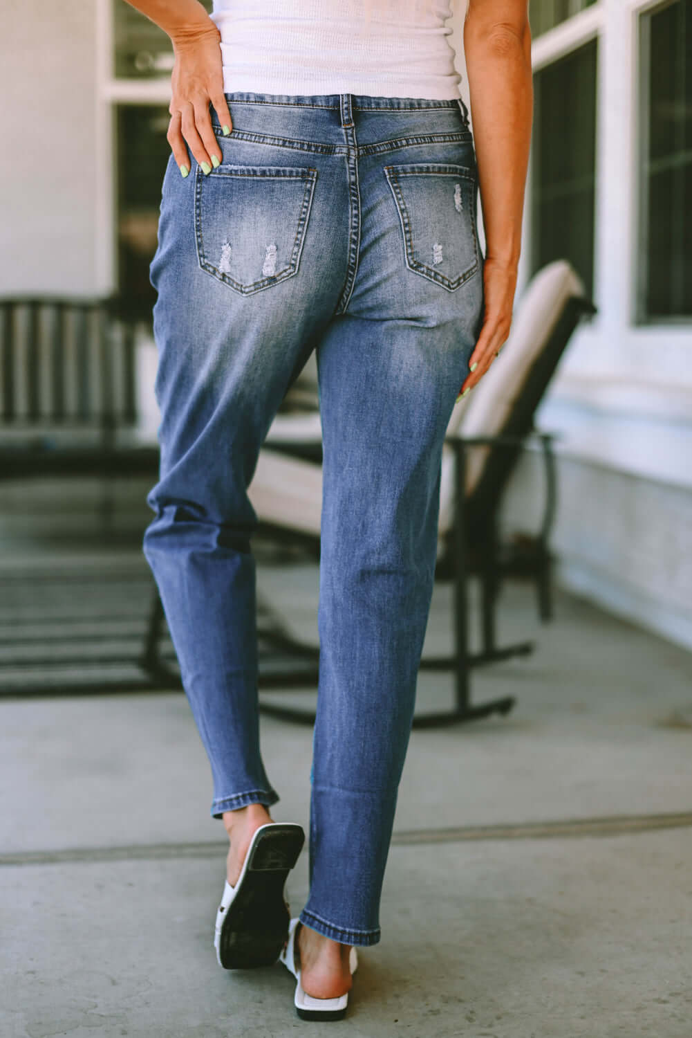 Back view of woman wearing Bella Road distressed straight jeans with pockets, slightly stretchy denim, outdoor setting.