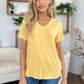 Woman wearing a yellow Bamboo V-Neck High-Low T-Shirt, featuring a basic style and slight stretch, made of 95% bamboo and 5% spandex.