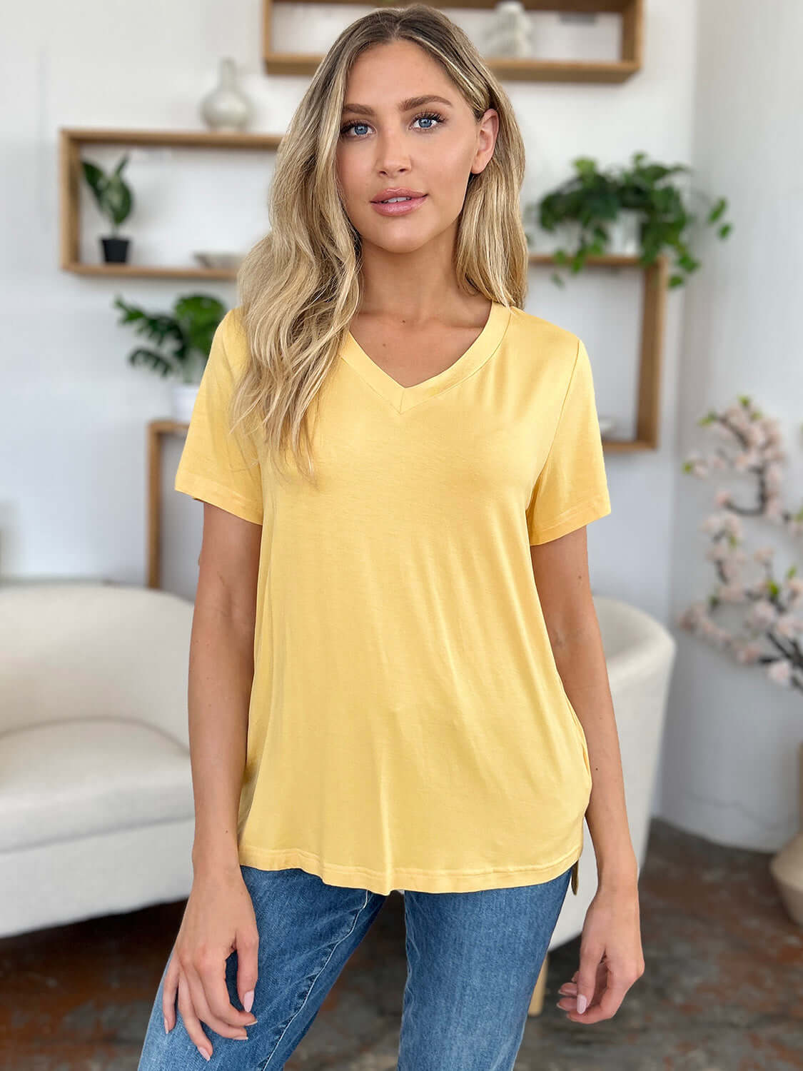 Woman wearing a yellow Bamboo V-Neck High-Low T-Shirt, featuring a basic style and slight stretch, made of 95% bamboo and 5% spandex.