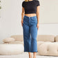 Woman wearing Crop Chloe full size Tummy Control High Waist Raw Hem Jeans in a living room setting. RFM Jeans for a stylish look.