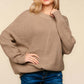 Woman wearing Haptics Full Size Side Slit Texture Asymmetric Sweater paired with blue jeans, showcasing the sweater's round neck and textured knit fabric.