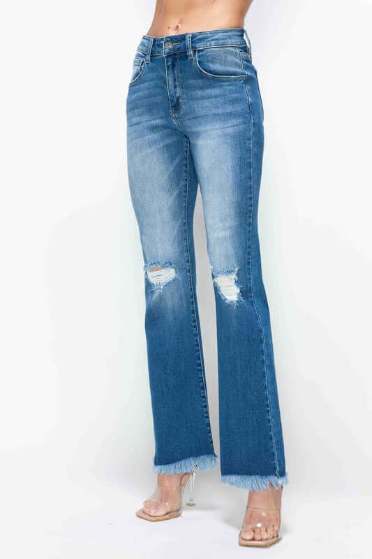 Distressed high rise bootcut jeans with raw hem, styled for a trendy and casual look. Perfect for pairing with boots or heels.