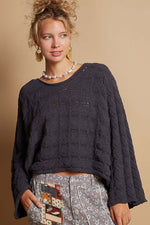 Woman wearing a blue round neck cable knit cropped sweater with full sleeves, paired with printed pants for a chic look.