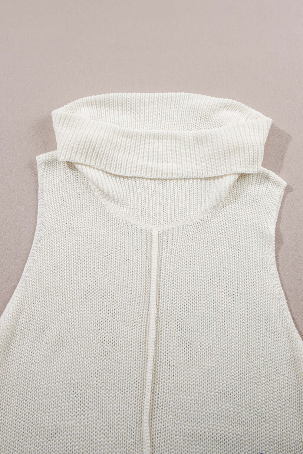 Close-up of Bella Road sleeveless white turtleneck sweater vest with a central seam detail on a neutral background.