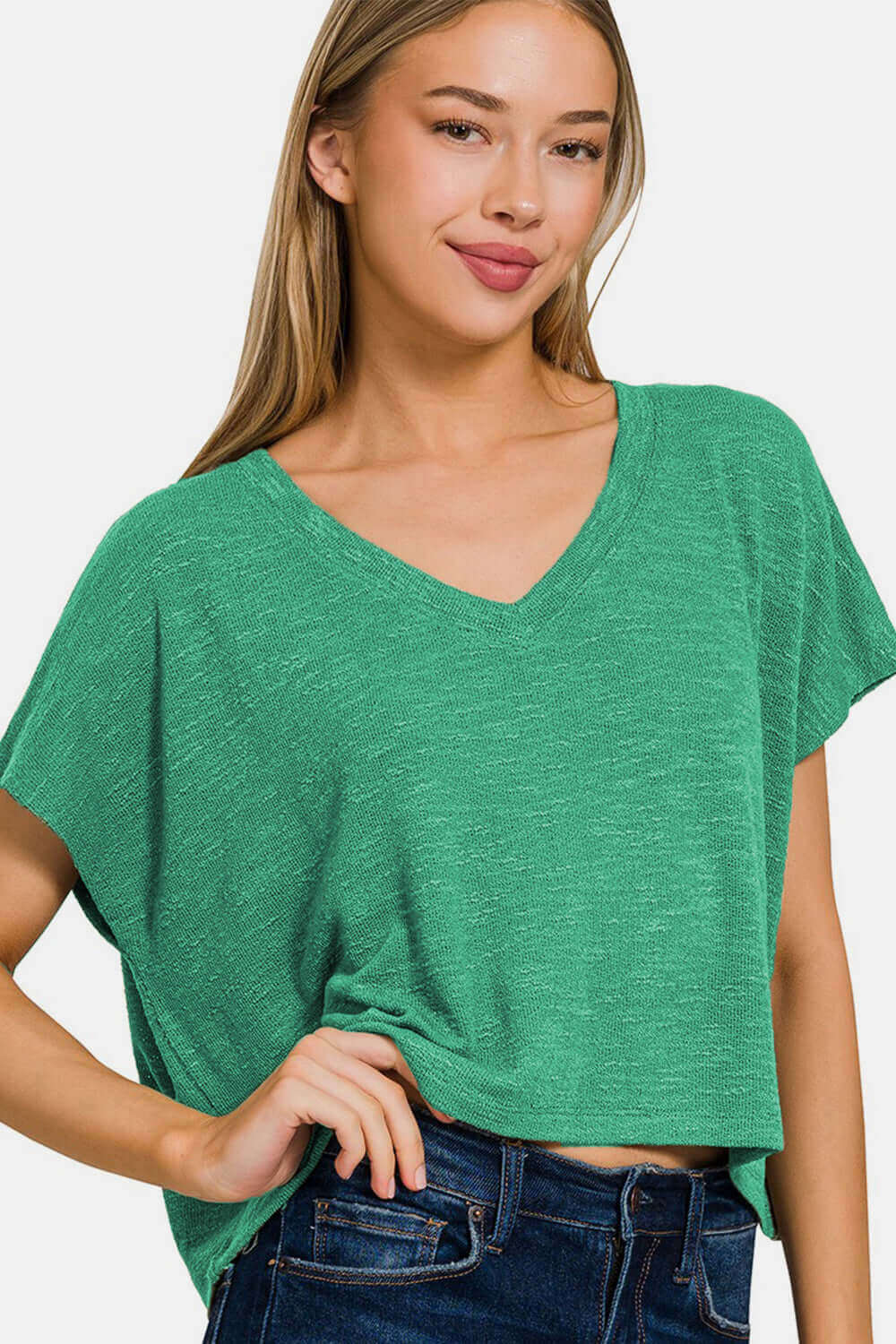 Woman wearing a green V-neck short sleeve T-shirt paired with jeans, showcasing casual and comfortable fashion style.