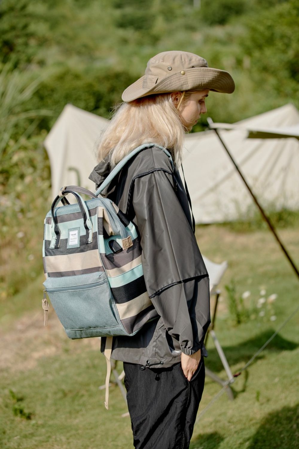 Person wearing Himawari Striped Waterproof Backpack with side pockets, perfect for outdoor adventures and stylish functionality.