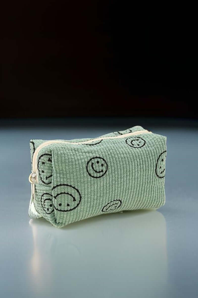 Small green corduroy cosmetic pouch with smiley face design, perfect for organizing makeup essentials and on-the-go touch-ups.