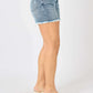 Side view of model wearing Button Fly Raw Hem Denim Shorts by Judy Blue Jeans