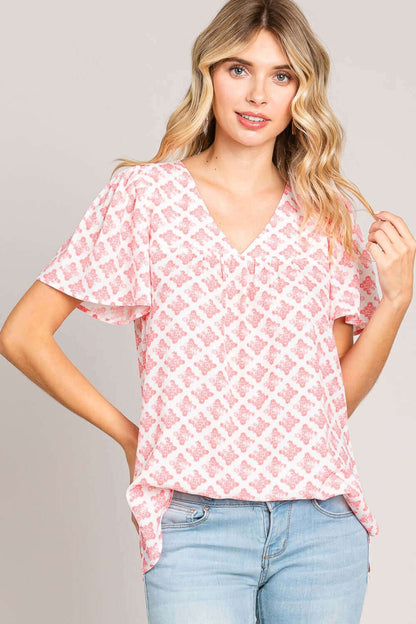 Woman wearing Slit Printed V-Neck Flutter Sleeve Blouse with pink pattern, showing delicate flutter sleeves and elegant V-neckline.