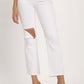 Woman modeling RISEN distressed cropped white jeans with a straight leg cut and edgy knee rip, paired with clear heels.