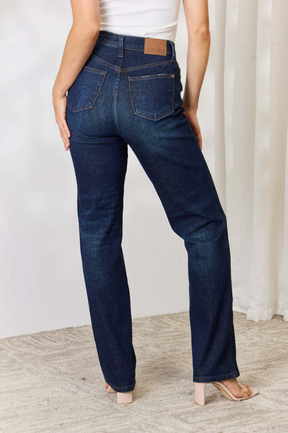 Woman wearing high-waist button-fly straight jeans by Judy Blue Jeans, crafted from premium lycra for a comfortable fit.