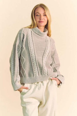 Cozy Davi & Dani cable-knit turtleneck sweater with dropped shoulders, perfect for stylish warmth in cool weather.