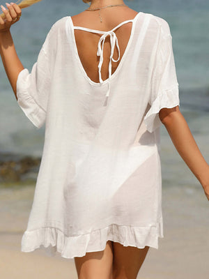 Woman wearing a white tied ruffled half sleeve cover-up on the beach.