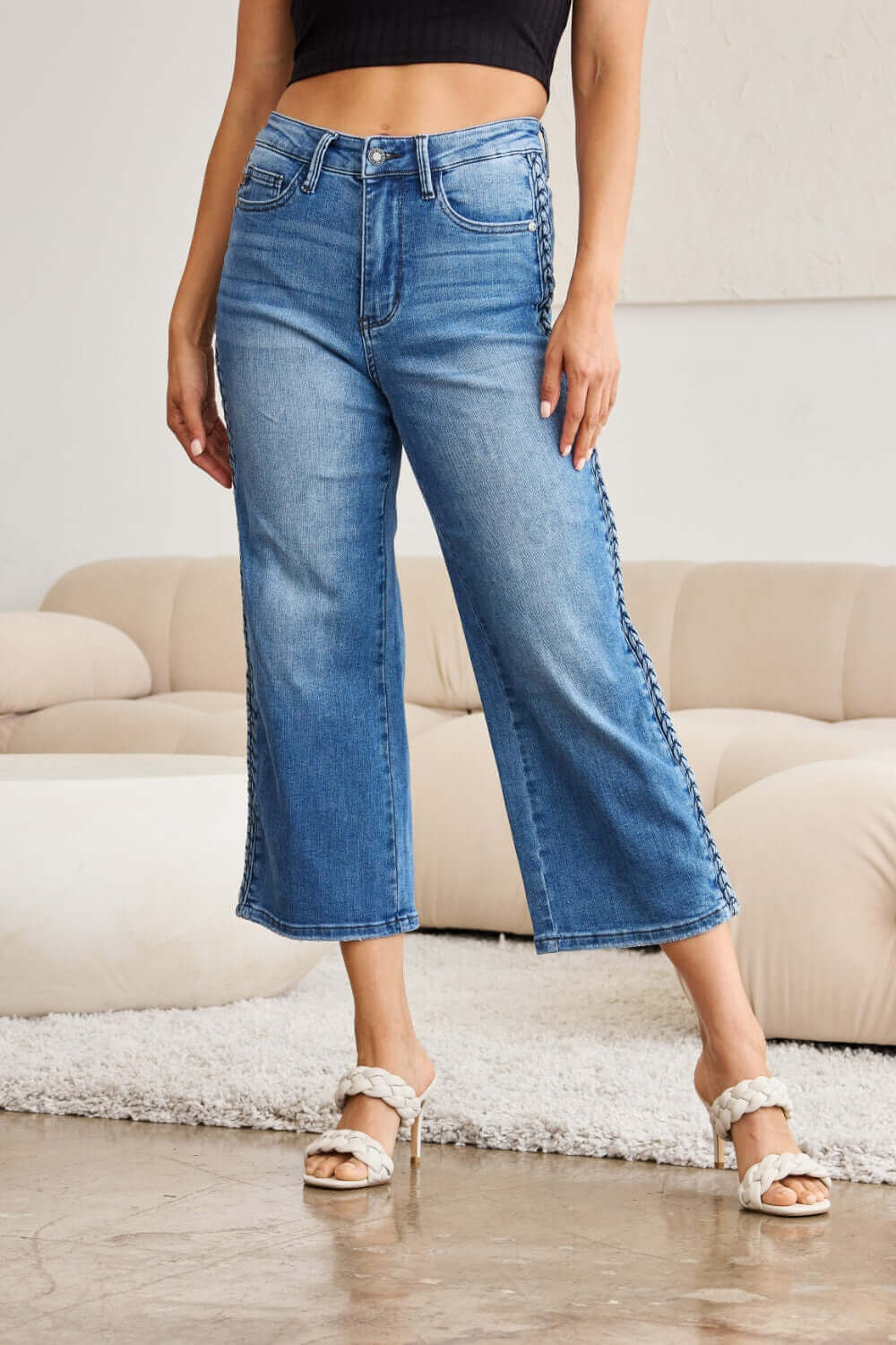 Woman wearing Judy Blue braid side detail wide leg jeans with unique braid design, stylish and chic, paired with white heels.