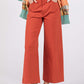 Wide-leg cropped pants with front pockets, button closure, and modern silhouette in burnt orange color.