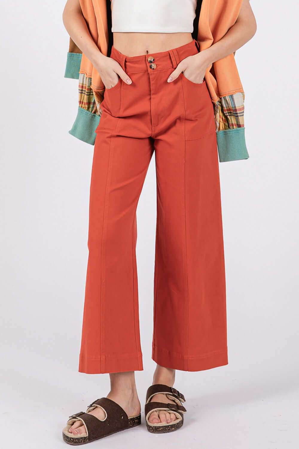 Wide-leg cropped pants with front pockets, button closure, and modern silhouette in burnt orange color.