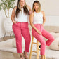 Two women modeling pink high waist jeans from RFM Jeans collection, highlighting tummy control and raw hem design, styled with white tops.