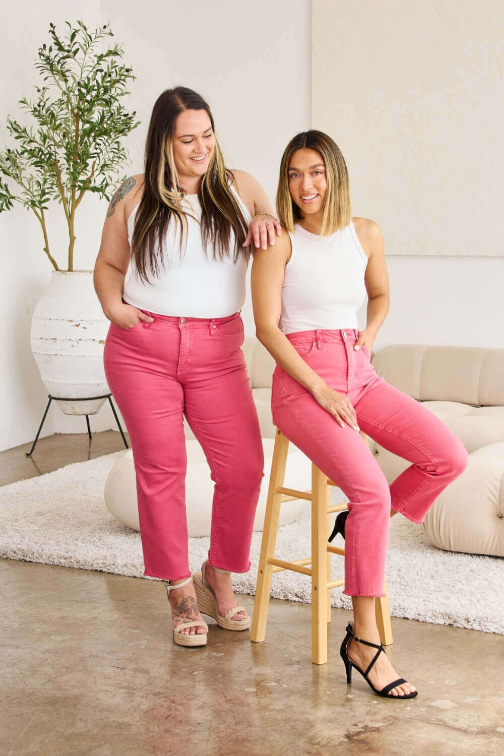 Two women modeling pink high waist jeans from RFM Jeans collection, highlighting tummy control and raw hem design, styled with white tops.