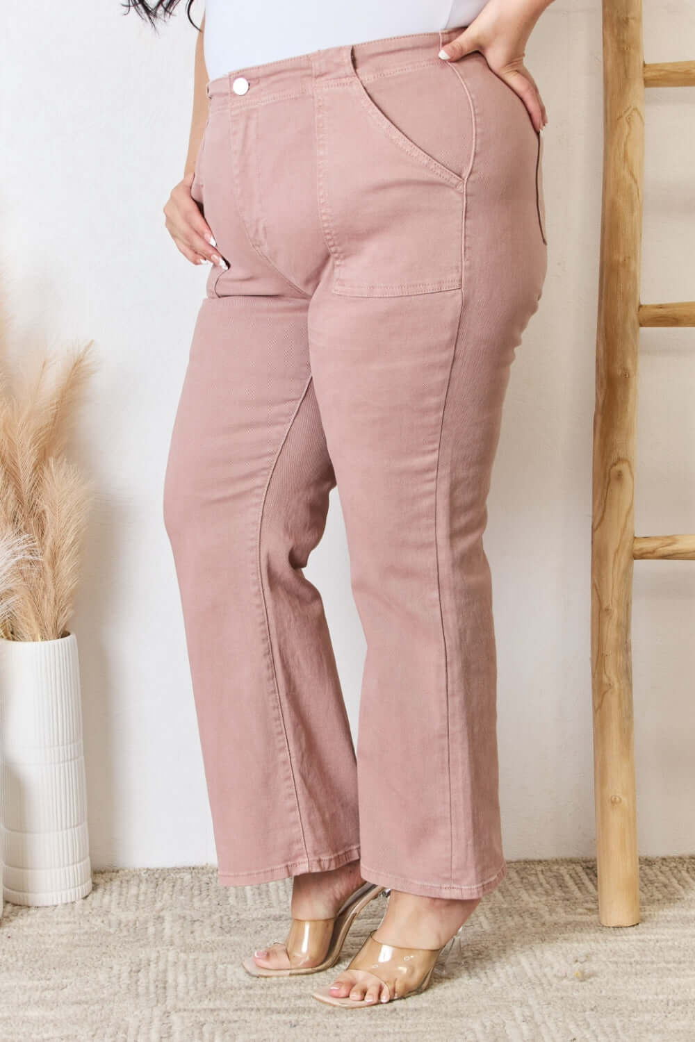 Model wearing Risen high-rise ankle flare jeans in pink, showcasing flattering silhouette with pocket details.