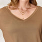 Woman wearing luxurious rayon long sleeve V-neck top in a neutral color, showing close-up detail of neckline and fabric texture.