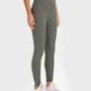 Woman wearing Millennia Highly Stretchy Wide Waistband Yoga Leggings in green, styled with a crop top and sneakers.