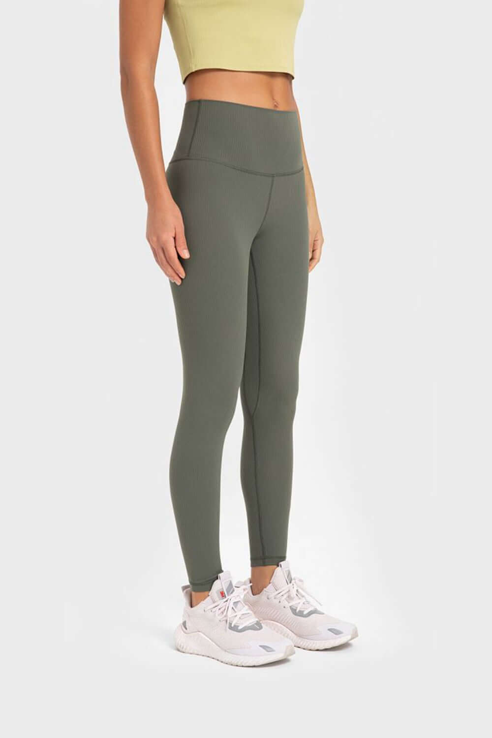 Woman wearing Millennia Highly Stretchy Wide Waistband Yoga Leggings in green, styled with a crop top and sneakers.