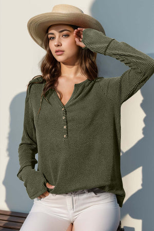 Woman wearing a Double Take Full Size Notched Thumbhole Long Sleeve T-Shirt in olive green with a hat, posing outdoors.