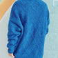 Woman wearing Bella Road Diamond Round Neck Long Sleeve Sweater in blue, featuring a unique diamond pattern and a comfortable fit.