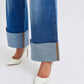 Distressed high waist wide leg jeans with folded cuffs, paired with stylish white stiletto heels on a light background.