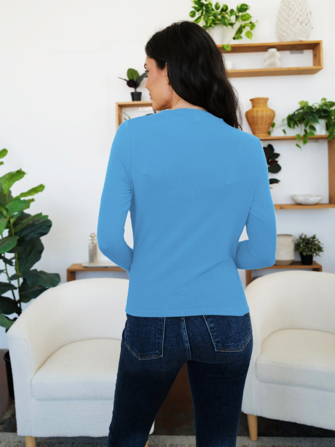 Woman wearing French Blue FAM-FAM Ruched Mock Neck Long Sleeve T-Shirt, standing in a cozy living room setting.